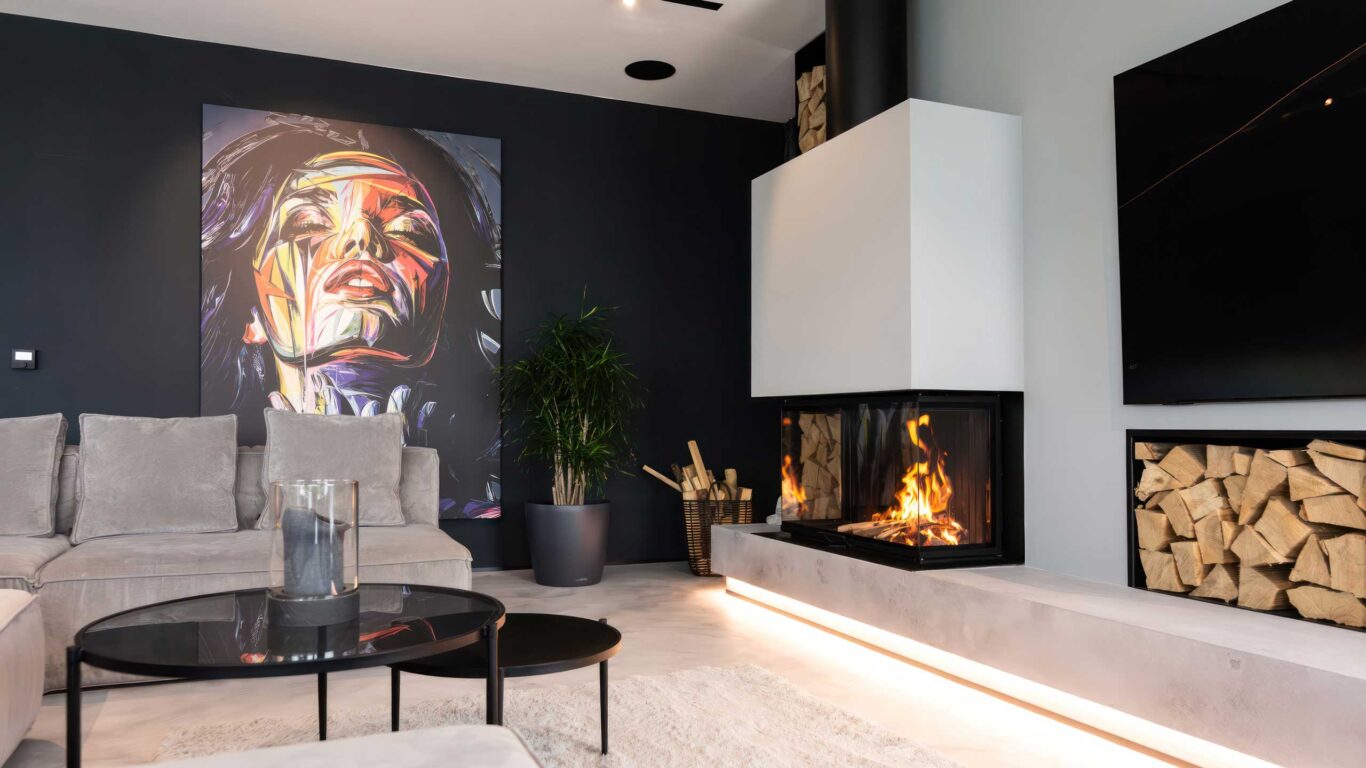 Moderner dreiseitiger Kamin mit integriertem TV Gerät, Holzablage und einer individuell einstellbaren LED Sockelbeleuchtung